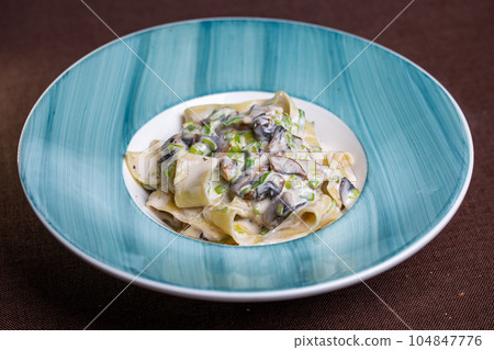 pasta with mushrooms and sauce in a blue plate 104847776
