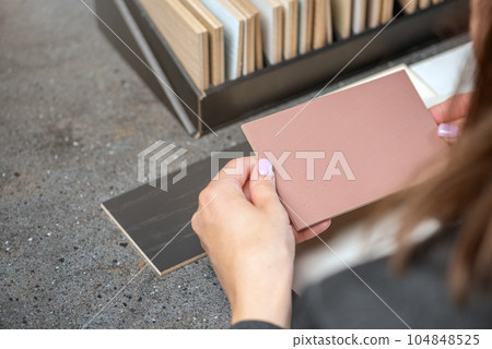 Choice of floor color from wood samples. A female designer chooses a floor color using samples of different shades. The concept of choosing a new floor. 104848525