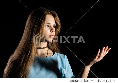 Close-up of a bust of a long-haired girl against a black background. 104849118