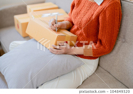 Starting small business entrepreneur of independent young Asian woman online seller is using computer and taking orders to pack products for delivery to customers. SME delivery concept. 104849320