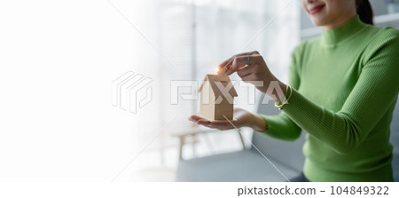 Asian women Property investment and house mortgage financial concept, Hand putting money coin stack with wooden house Asian women Property investment and house mortgage financial concept, Hand putting money coin stack with wooden house 104849322