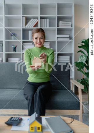 Asian women Property investment and house mortgage financial concept, Hand putting money coin stack with wooden house Asian women Property investment and house mortgage financial concept, Hand putting money coin stack with wooden house 104849348