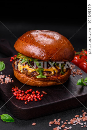 Burger with juicy beef cutlet, cheese, tomatoes, salt, spices and herbs 104849369