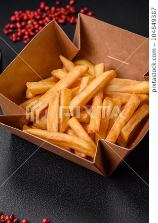 Delicious crispy french fries with salt and spices in a cardboard box Delicious crispy french fries with salt and spices in a cardboard box 104849387