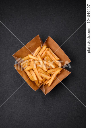 Delicious crispy french fries with salt and spices in a cardboard box Delicious crispy french fries with salt and spices in a cardboard box 104849407