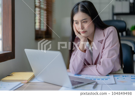 Portrait of a young Asian woman showing acute headache from sitting for a long time at work Portrait of a young Asian woman showing acute headache from sitting for a long time at work 104849498