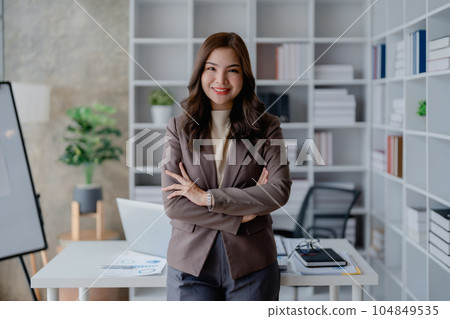 Portrait of a woman business owner showing a happy smiling face as he has successfully invested her business using computers and financial budget documents at work. Portrait of a woman business owner showing a happy smiling face as he has successfully invested her business using computers and financial budget documents at work. 104849535