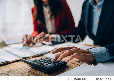 Two business people meeting to talking or discuss marketing work in workplace using paperwork, calculator, computer to work. 104849635