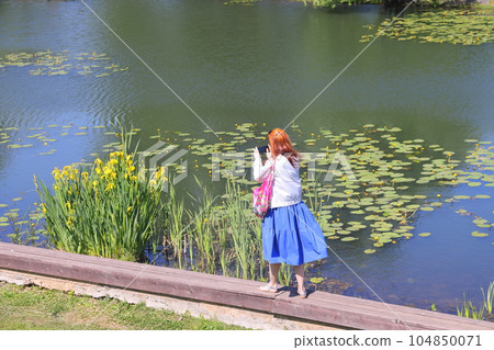 Girl, young woman takes a picture of the landscape around Lake. Girl, young woman takes a picture of the landscape around Lake. 104850071