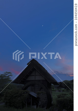 The moon, age 5.9, floating above the water mill in Takegawa-cho, Hokuto City, in the clouds at sunset 104850419