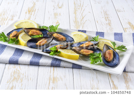 Cooked mussels with lemon and parsley on wooden table, selective focus. 104850748