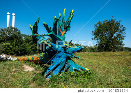 A blue painted tree trunk laying in the lawn nearby the river Isar at Munich, Bavaria, Germany A blue painted tree trunk laying in the lawn nearby the river Isar at Munich, Bavaria, Germany 104851324