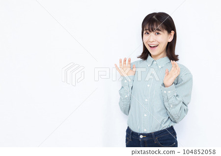 A woman in her thirties who is surprised with a smile in front of a white background 104852058