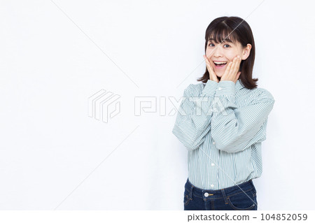 A woman in her thirties who is surprised with a smile in front of a white background 104852059