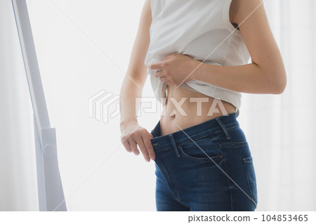 Woman checking her stomach in the mirror Woman checking her stomach in the mirror 104853465