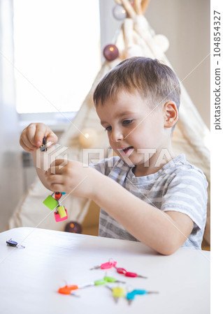 The child works with Montessori material with colored locks. Picks up keys. Develops fine motor skills. The child works with Montessori material with colored locks. Picks up keys. Develops fine motor skills. 104854327