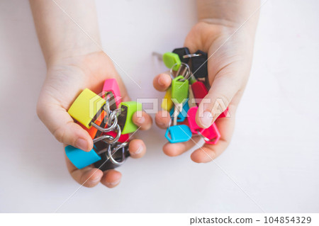 The child works with Montessori material with colored locks. Picks up keys. Develops fine motor skills. 104854329