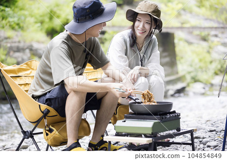 A young man and woman making yakisoba on a gas stove on a riverbed Outdoor image 104854849