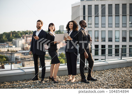 Corporate partners operating modern gadgets on rooftop 104854894