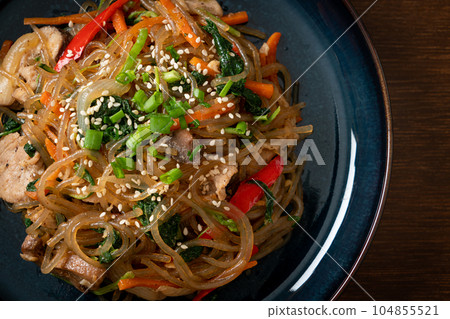 japchae or stir-fried Korean vermicelli noodles with vegetables and pork topped with white sesame 104855521