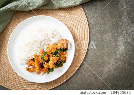 stir-fried fried fish with basil and chili in thai style topped on rice 104855683