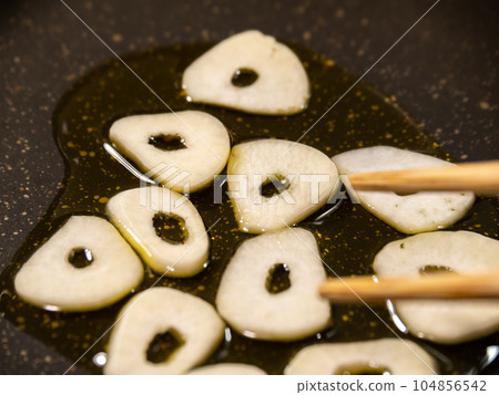 A cooking scene where garlic (slices) is fried with olive oil. A cooking scene where garlic (slices) is fried with olive oil. 104856542