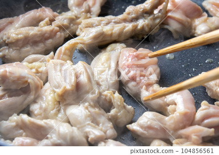 A cooking scene where chicken (young chicken seseri) is fried in a frying pan. A cooking scene where chicken (young chicken seseri) is fried in a frying pan. 104856561
