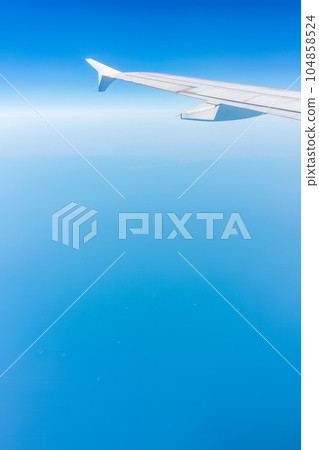View from the airplane window at a beautiful cloudy sky and the airplane wing 104858524