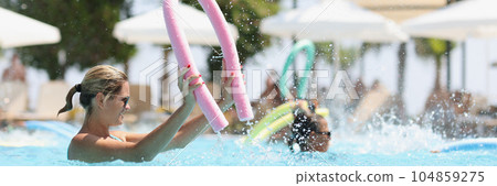 Beautiful woman in sunglasses swims in pool of luxury hotel. 104859275