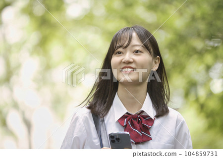 A high school girl with a smartphone in the fresh green 104859731