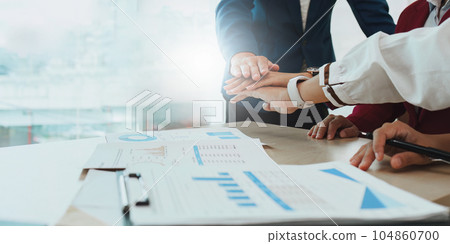 Diverse business team stacking hands and collaboration and analyze financial data for long term investments 104860700