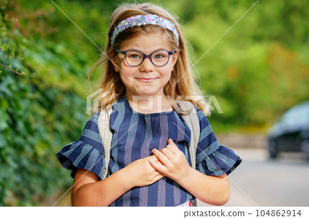 Little Preschool Girl on the Way to School. Healthy Happy Child Walking to Nursery School and Kindergarten. Smiling Child with Eyeglasses and Backpack on the City Street, Outdoors. Back to School. 104862914
