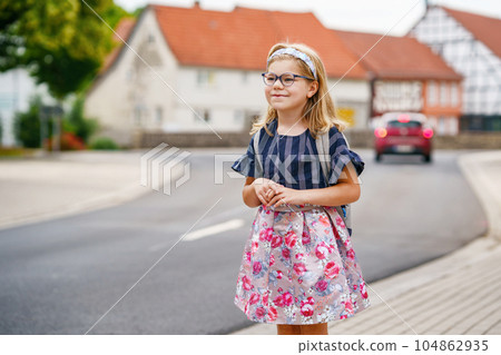 Little Preschool Girl on the Way to School. Healthy Happy Child Walking to Nursery School and Kindergarten. Smiling Child with Eyeglasses and Backpack on the City Street, Outdoors. Back to School. 104862935