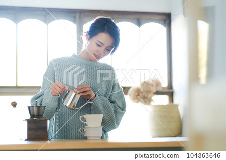 A woman who is making coffee 104863646