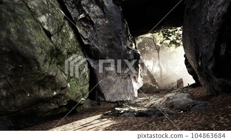 Shaft of light beaming down into large cave 104863684