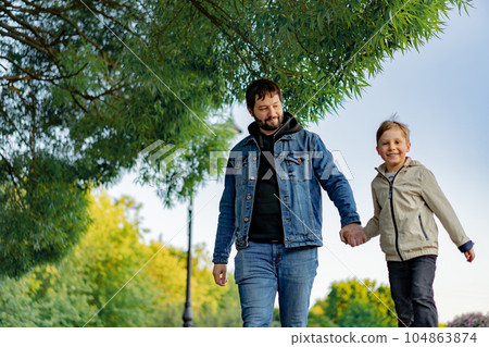 Caucasian bearded man with his little son walking in park holding hands 104863874