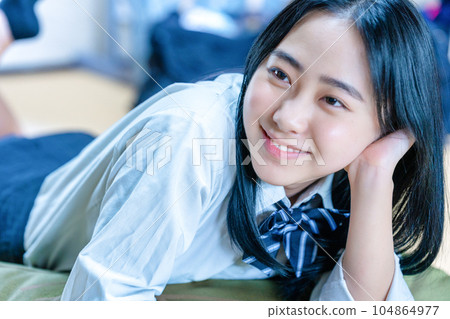 A high school girl lying down while wearing a uniform A high school girl lying down while wearing a uniform 104864977