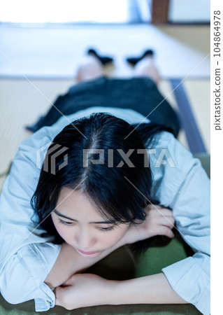 A high school girl lying down while wearing a uniform A high school girl lying down while wearing a uniform 104864978