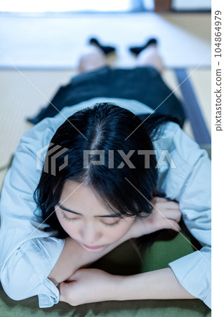A high school girl lying down while wearing a uniform 104864979