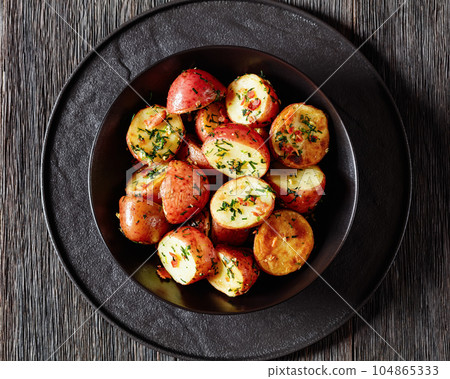 Herbs Garlic Potatoes in black bowl, top view 104865333