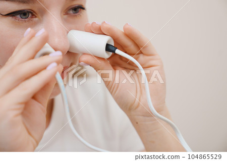 A patient on a magnetotherapy procedure on the nose 104865529