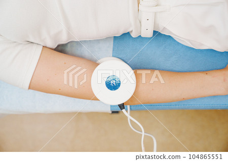 A patient on a magnetotherapy procedure on hand. 104865551