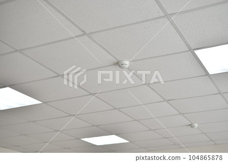 A fire sensor on the ceiling. Armstrong ceiling. A fire sensor on the ceiling. Armstrong ceiling. 104865878