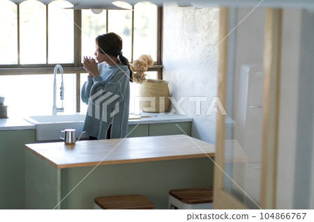 一名婦女飲用的咖啡在廚房裡 一名婦女飲用的咖啡在廚房裡 104866767