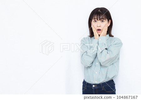 A woman in her thirties who is surprised in front of a white background 104867167