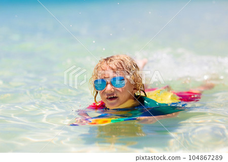 Kids surf on tropical beach. Vacation with child. Kids surf on tropical beach. Vacation with child. 104867289