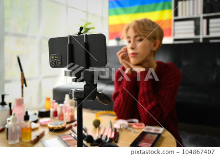 Pretty young gay man beauty make up artist recording makeup tutorial to share on social media 104867407