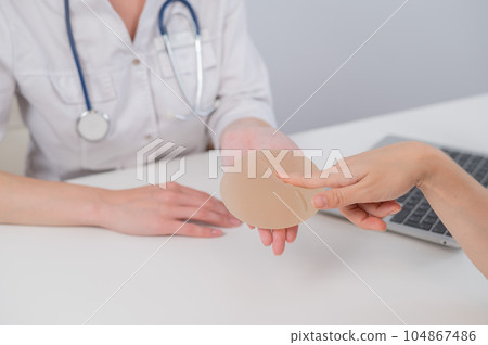 Caucasian woman and plastic surgeon touching and choosing breast implants. Caucasian woman and plastic surgeon touching and choosing breast implants. 104867486