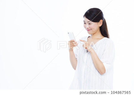 一名三十多歲的女性在白色背景前操作智能手機 104867565