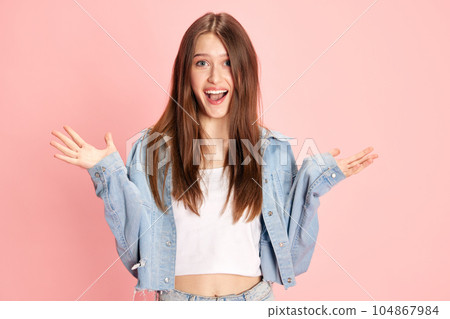 Portrait of beautiful, young excited woman in casual clothes showing happiness and joy against pink studio background Portrait of beautiful, young excited woman in casual clothes showing happiness and joy against pink studio background 104867984